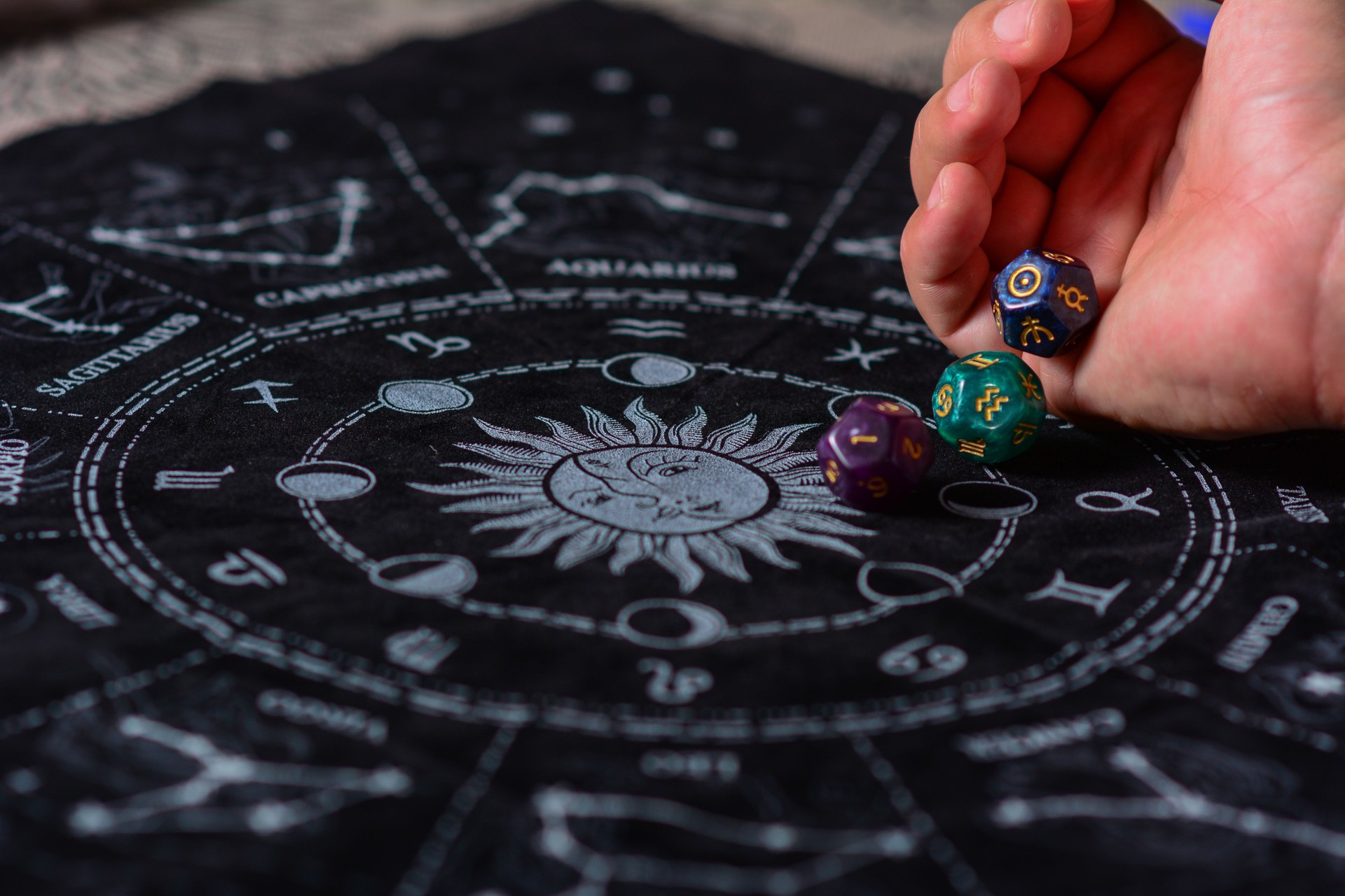 Mãos masculinas com três cubos de astrologia com símbolos astrológicos sobre um fundo preto do Zodíaco Table Chart com círculo mágico